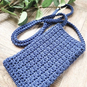 May include: A small blue crocheted bag with a long strap. The bag is made with a simple stitch pattern and has a slightly textured surface.