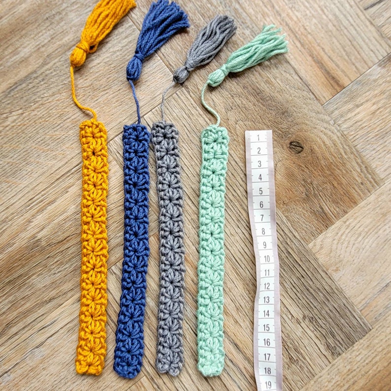 May include: Five crocheted bookmarks with tassels in yellow, blue, gray, green, and a ruler measuring 19 inches.