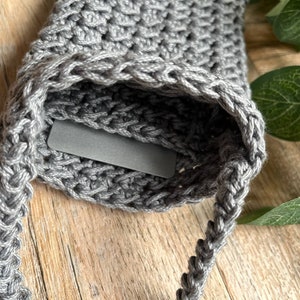 May include: Gray crocheted bag with a braided strap. The bag has a small pocket on the front.