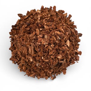 May include: A pile of brown, irregularly shaped wood chips, possibly bark, against a white background. The chips vary in size and texture, with a mix of light and dark brown tones. The overall appearance suggests a natural, organic material.