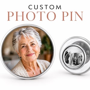 May include: A custom photo pin with the text "CUSTOM PHOTO PIN" at the top. The pin features a silver border and a photo of a smiling woman. The pin's back is also visible, showing the clasp.