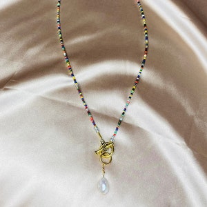 May include: A colorful beaded necklace with a gold toggle clasp and a pearl pendant.