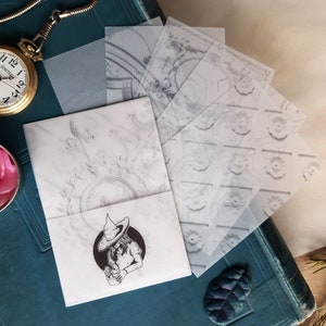 Puede incluir: Un conjunto de seis hojas de papel translúcidas con patrones. Las hojas están superpuestas y tienen una variedad de diseños, que incluyen un patrón repetitivo de círculos, un diseño con un motivo floral y un diseño con un patrón geométrico. Las hojas están sobre una superficie azul oscuro.