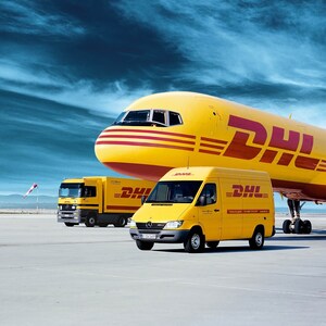 May include: A yellow DHL airplane, truck, and van are parked on a concrete surface. The vehicles and aircraft have the DHL logo in red. The sky is blue with white clouds. The airplane is the largest vehicle in the image.