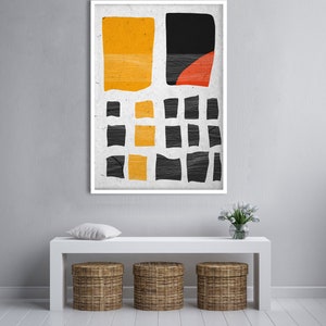 May include: Abstract art print in a white frame. The artwork features a textured, off-white background with yellow, black, and red geometric shapes. The shapes include rectangles and a semi-circle, creating a modern aesthetic.