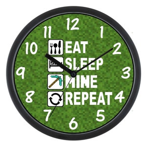 May include: A black and green round clock with white numbers and a Minecraft-themed design. The clock face features the text "Eat Sleep Mine Repeat" with icons representing each activity.