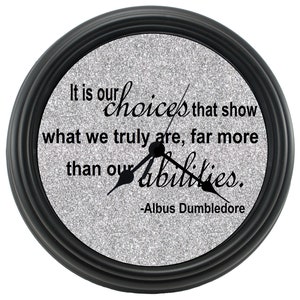May include: Black clock with a silver glitter face and a quote from Albus Dumbledore: "It is our choices that show what we truly are, far more than our abilities."