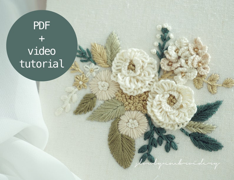 May include: Close-up of an embroidered floral design featuring cream-colored, beige, and green thread. The design includes large, textured flowers, smaller blossoms, and detailed leaves. Text in a circle reads "PDF + video tutorial".