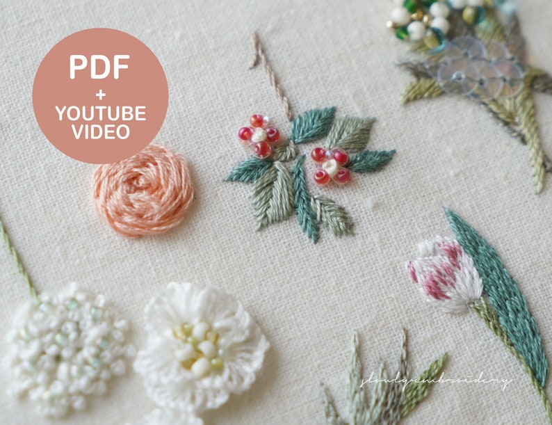 以下が含まれることがあります： クリーム色の生地に刺繍された花のクローズアップ。バラ、チューリップ、その他の詳細な花柄など、さまざまな花が写っています。「PDF + YOUTUBE VIDEO」というテキストがピンク色の円の中にあります。