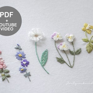 May include: Embroidered floral designs in pink, blue, white, and yellow. The image includes the text "PDF + YOUTUBE VIDEO" in a gray circle. The flowers are stitched on a white background, showcasing detailed needlework.