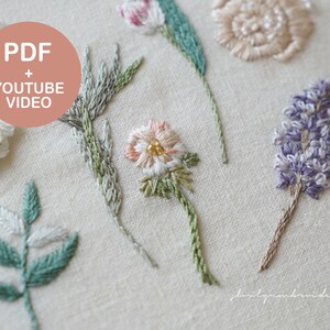 以下が含まれることがあります： 白、ピンク、紫の花、緑とグレーの葉など、さまざまな刺繍の花柄のデザインのクローズアップ。 「PDF + YOUTUBE VIDEO」というテキストがピンク色の円の中にあります。 刺繍は薄いベージュ色の生地に施されています。
