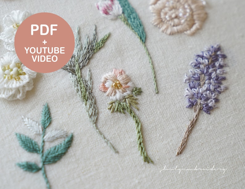 以下が含まれることがあります： 白、ピンク、紫の花、緑とグレーの葉など、さまざまな刺繍の花柄のデザインのクローズアップ。 「PDF + YOUTUBE VIDEO」というテキストがピンク色の円の中にあります。 刺繍は薄いベージュ色の生地に施されています。