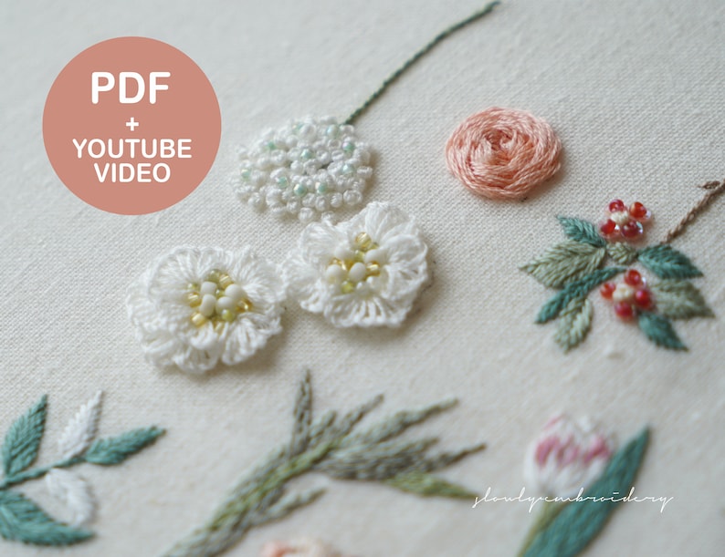 以下が含まれることがあります： クリーム色の生地に刺繍された花のクローズアップ。白、桃色、緑色の手縫いの花がいくつかあり、ビーズのアクセントが付いています。ピンクの円の中のテキストは「PDF + YOUTUBE VIDEO」と書かれています。