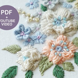 May include: Close-up of a floral embroidery design featuring various flowers in shades of blue, peach, and cream, with green leaves. The embroidery includes bead accents and is set against a white fabric background. Text on the image reads "PDF + YOUTUBE VIDEO".