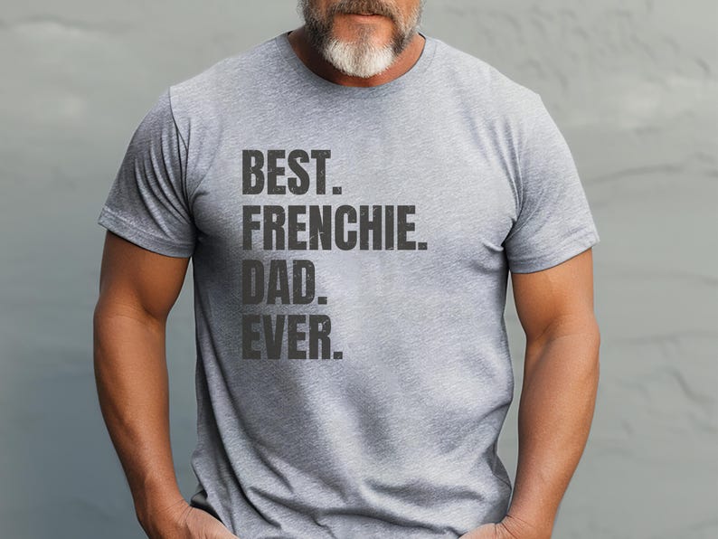 May include: A heather gray t-shirt with the text "BEST. FRENCHIE. DAD. EVER." in a bold, dark gray font. The shirt is short-sleeved and appears to be made of a soft, comfortable material.