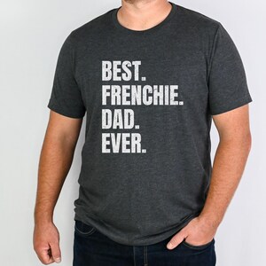 May include: Dark gray t-shirt with the text "BEST. FRENCHIE. DAD. EVER." in white block letters. The shirt is a crew neck style and is being worn by a person.