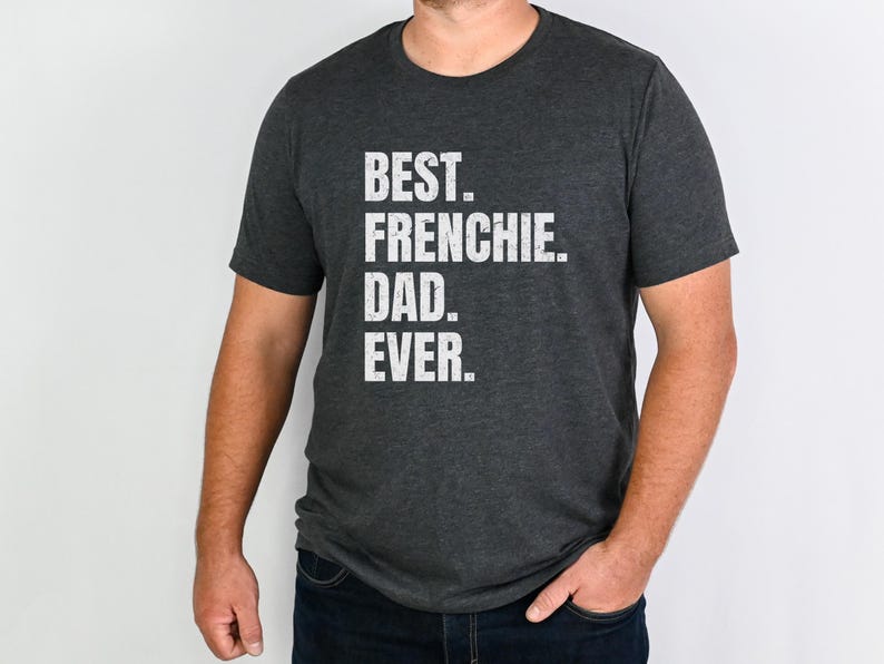 May include: Dark gray t-shirt with the text "BEST. FRENCHIE. DAD. EVER." in white block letters. The shirt is a crew neck style and is being worn by a person.