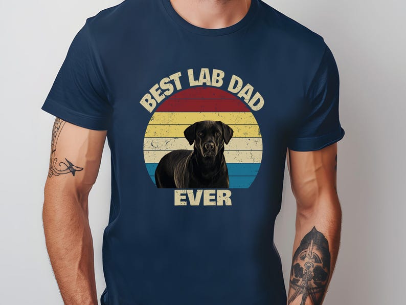 May include: Dark blue t-shirt with a retro design. It features a black Labrador Retriever inside a sunset circle. The text reads "BEST LAB DAD EVER" in a vintage font, ideal for dog lovers.