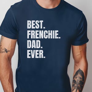 May include: Navy blue t-shirt with the white text "BEST. FRENCHIE. DAD. EVER." The shirt is a solid color and has a crew neck. The text is in a bold, sans-serif font.