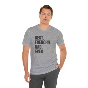 May include: A heather gray t-shirt with the text "BEST. FRENCHIE. DAD. EVER." in black. The shirt is worn by a person, and the overall style is casual and comfortable.
