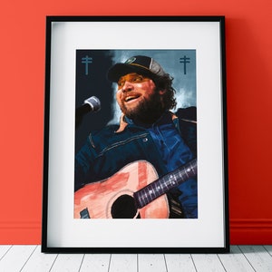 May include: A man with a beard and a baseball cap sings into a microphone while holding an acoustic guitar. The background is a blurred blue and white image with the text "†" on either side of the image.