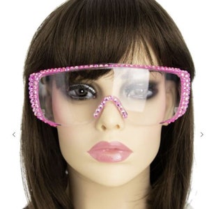 May include: Pink clear plastic sunglasses with rhinestones around the frame.