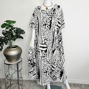 May include: A white ceramic mug with a black handle and the text "But First, Coffee" in a black, bold font. The mug is on a white surface. The mug is approximately 4 inches tall.