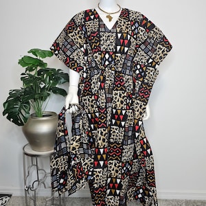 May include: A white ceramic mug with a black handle and the text "But First, Coffee" in a bold, black font. The mug is set against a blurred background, suggesting a cosy setting.