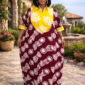 May include: A long, flowing dress with a maroon background and white and yellow patterns. The dress features a yellow collar and cuffs, and a white leaf-like design on the bodice. The dress is worn outdoors.