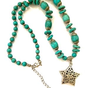 May include: A turquoise and silver necklace with a star pendant. The necklace is made of round and oval beads with a silver clasp.