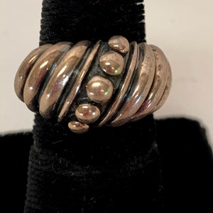May include: A silver ring with a twisted band and a row of round beads.