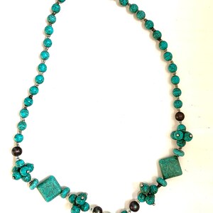 May include: A turquoise necklace featuring a bear pendant. The necklace is made from round beads and has a silver clasp. The bear pendant is also made of turquoise and has a detailed design.