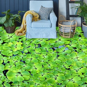 May include: A close-up of a green and black patterned floor covering that looks like a pond with lily pads. The floor covering is in front of a blue wall and a chair with a yellow throw blanket.