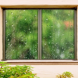Puede incluir: Una ventana con vista a árboles y follaje verdes. La ventana está cubierta de gotas de lluvia, creando un efecto borroso. El marco de la ventana es gris y la pared es de color beige claro.