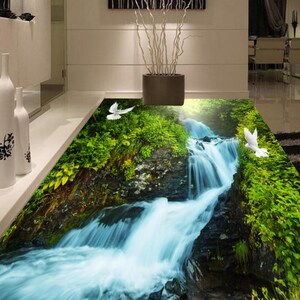 Puede incluir: Una calcomanía de suelo 3D que representa una cascada que cae por un acantilado rocoso, rodeada de exuberante vegetación verde. Dos palomas blancas vuelan sobre la cascada, creando una escena serena y tranquila.