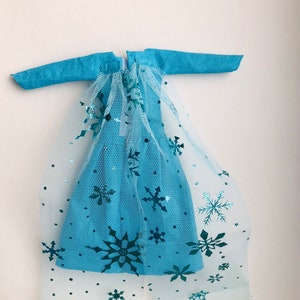 K&ouml;nnte beinhalten: Ein blaues Kleid mit einem T&uuml;ll&uuml;berzug mit Schneeflocken-Designs. Das Kleid hat lange &Auml;rmel und einen Rei&szlig;verschluss auf der R&uuml;ckseite.