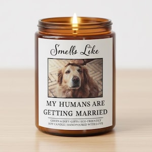 May include: A lit soy candle in a brown glass jar. The label reads "Smells Like" above a photo of a golden retriever. Below the photo, the text says "MY HUMANS ARE GETTING MARRIED".
