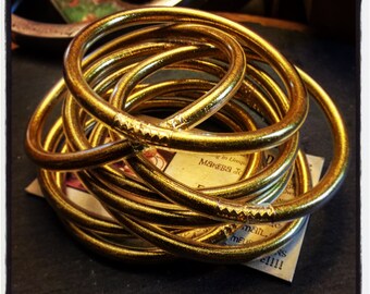 Könnte beinhalten: Ein Stapel goldener Glitzerarmbänder. Die Armbänder sind übereinander gestapelt und in einem kreisförmigen Muster angeordnet.