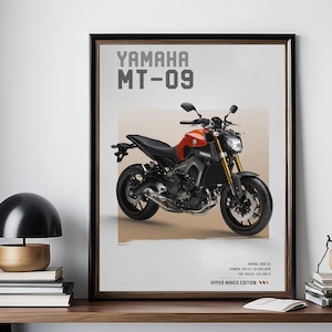 Può includere: Poster incorniciato con una motocicletta Yamaha MT-09. La moto è nera e arancione con dettagli dorati. Il poster include il testo "YAMAHA MT-09" e specifiche tecniche. Il poster è esposto su una scrivania di legno.