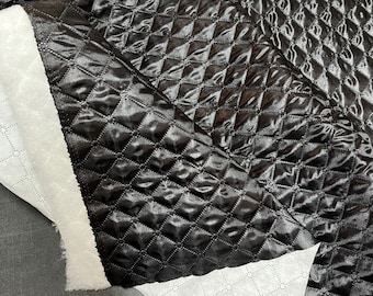 Op de afbeelding: Zwarte quilted stof met een ruitpatroon. De stof is zacht en heeft een lichte glans.