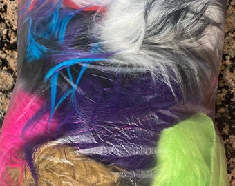 May include: A plastic bag filled with colorful faux fur. The fur is in various colors, including pink, blue, green, purple, white, and black.