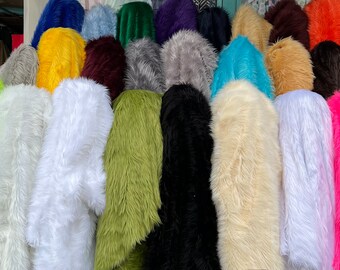 May include: A variety of faux fur fabrics in different colors, including green, white, black, pink, and yellow. The fabrics are displayed in a shop setting.
