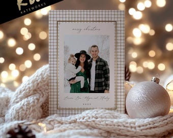 May include: A Christmas card with a family photo inside a gingham patterned frame. The card has the words "merry christmas" and a family name. A white and gold logo is in the upper left corner. A decorative ornament and a knitted blanket are in the foreground.