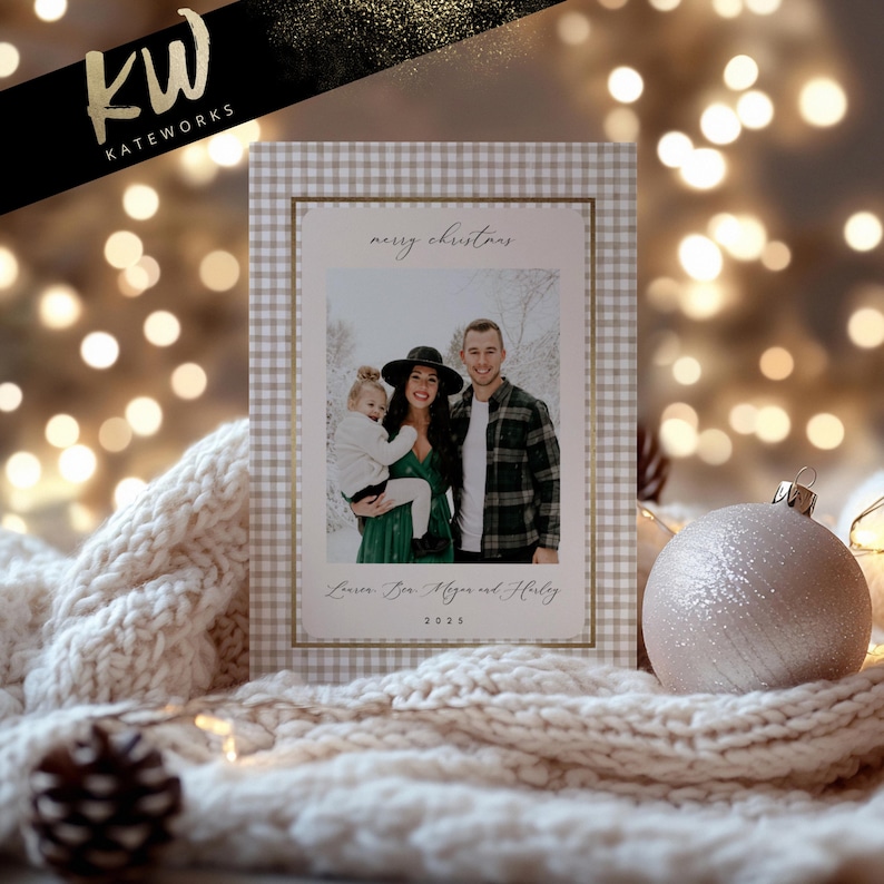 May include: A Christmas card with a family photo inside a gingham patterned frame. The card has the words "merry christmas" and a family name. A white and gold logo is in the upper left corner. A decorative ornament and a knitted blanket are in the foreground.