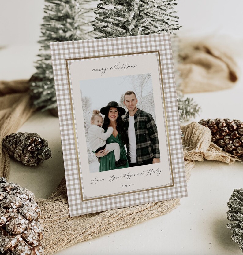 May include: A Christmas card with a family photo inside a gold-bordered frame. The card has a tan and white gingham pattern. The words "merry christmas" are at the top, and the family's names and the year 2025 are at the bottom.