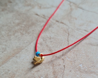 Handgemaakte vergulde ketting met vogelbedeltje: blauwe kralenketting met rood koord.