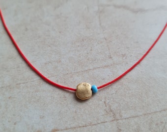 Handgemaakte ketting met 14-karaats vergulde schijfjes: delicate choker met blauwe kralen en rood koord.
