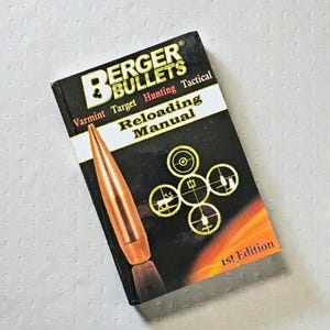 May include: A black and white "Berger Bullets Reloading Manual" with a copper-colored bullet illustration. The cover includes the text "Varmint Target Hunting Tactical" and "1st Edition". The manual features diagrams.