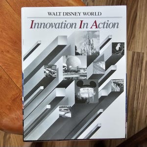 以下が含まれることがあります： 「Innovation In Action」というタイトルと、上部に「Walt Disney World」という言葉が書かれた本の表紙。シンデレラ城やスペースシップアースなど、ディズニーワールドの画像をコラージュした表紙です。