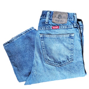 May include: A pair of blue denim jeans with a brown leather patch that says "Premium Quality Wrangler" and a red patch that says "Wrangler".